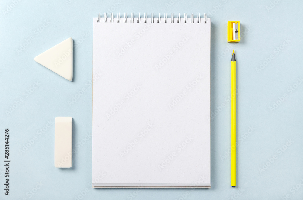 White notebook, pencil sharpener, pencil and eraser. Top view with copy space. White notebook, pencil sharpener, pencil and eraser. Top view with copy space.