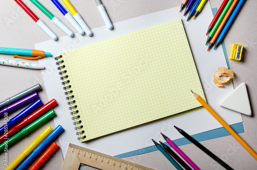 Yellow notebook, ball pen, pencil sharpener, ruler, pencil and eraser lie in the workplace of a schoolboy.