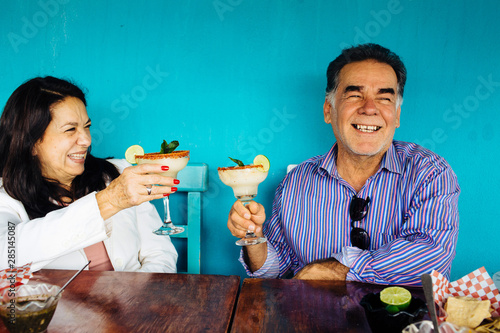 Hispanic Mexican woman and man senior couple celebrating cheering with margarita drink, Mexico