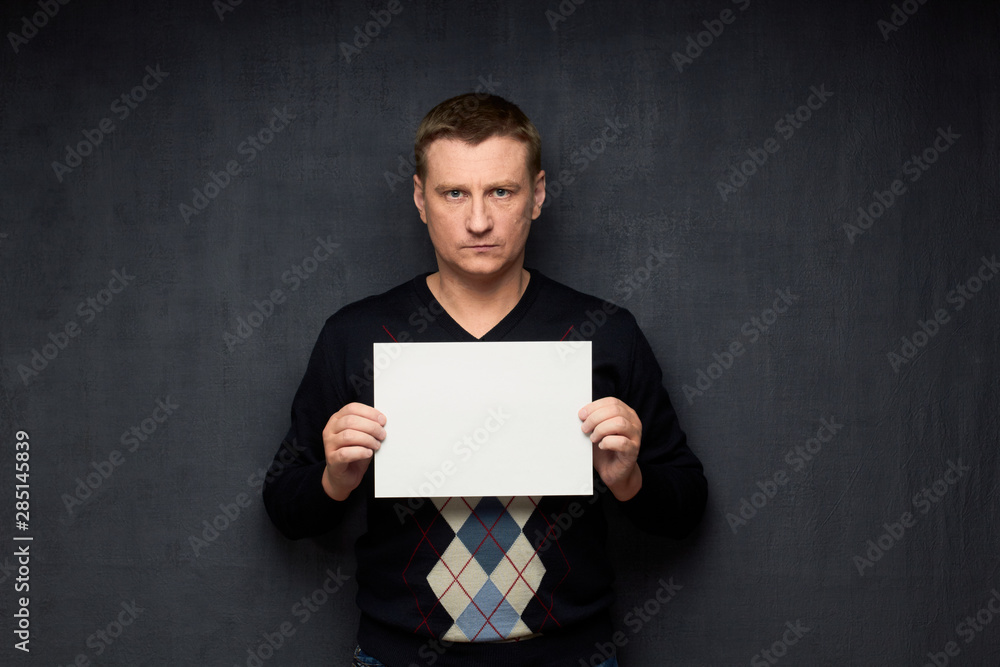 Portrait of serious man holding white blank paper sheet Portrait of serious man holding white blank paper sheet