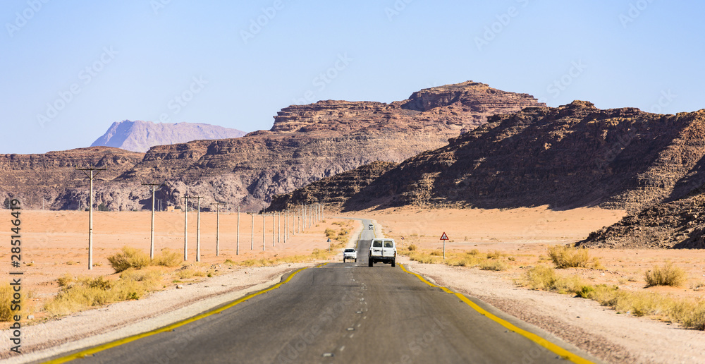 (Selective focus) Stunning view of the famous Kings highway, beautiful curvy road running through the Wadi Rum desert with rocky mountains in the distance. Jordan.