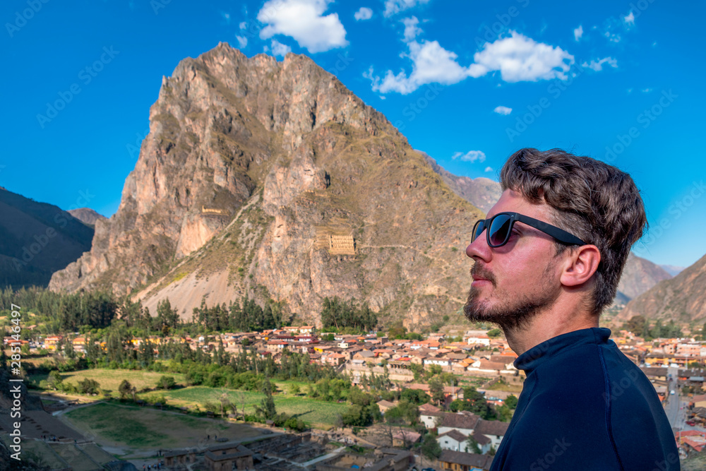 A man tourist in profile with sun glasses, with the background of the city of Ollantaytambo, Sacred Valley of the Incas.