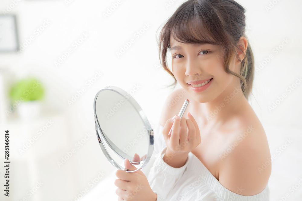 Beautiful portrait young asian woman looking mirror applying makeup lipstick at room, beauty lips asia girl makeup and cosmetic fashion on mouth at home, lifestyle and health care concept. Beautiful portrait young asian woman looking mirror applying makeup lipstick at room, beauty lips asia girl makeup and cosmetic fashion on mouth at home, lifestyle and health care concept.