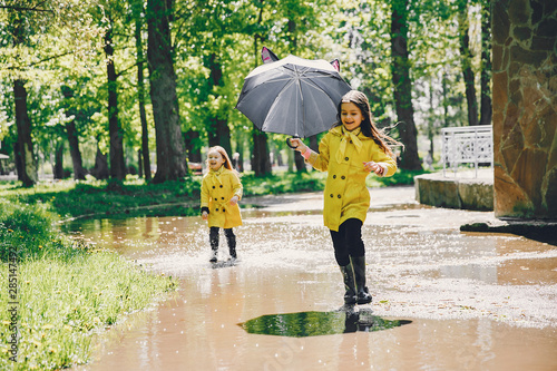 Kids in a rain coats. Children in a park. Two cute sisters