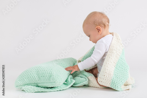 Kid with the plush sriped double colored blanket on the white background