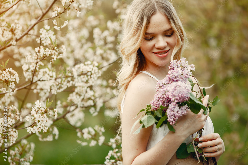 Fototapeta premium Beautiful girl in a white dress. Woman in a spring blooming park