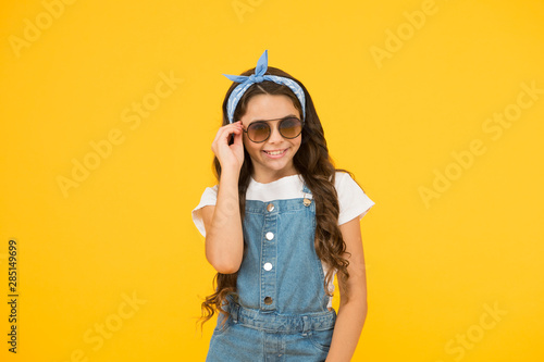 Summer vacation concept. Girl long curly hair sunglasses tied headscarf. Kids clothes boutique. Summer accessories. Vacation mode on. Summer trend. Little fashionista. Cute small kid fashion girl