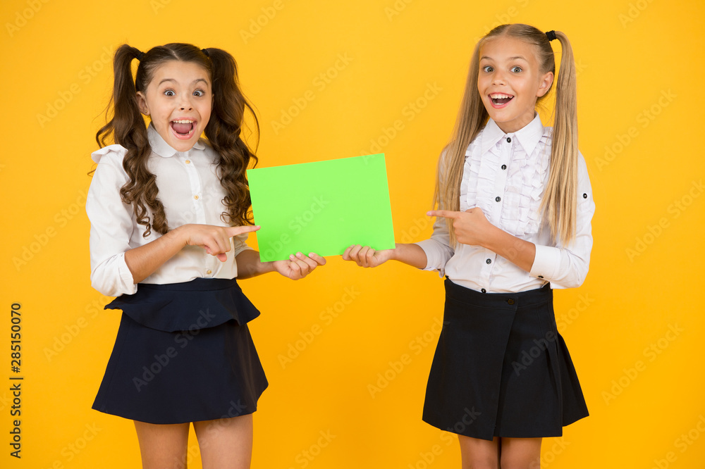 Girls school uniform hold poster. Back to school concept. Schoolgirls show poster. Social poster copy space. Socialization involves how children get along with each other. School socialization Girls school uniform hold poster. Back to school concept. Schoolgirls show poster. Social poster copy space. Socialization involves how children get along with each other. School socialization