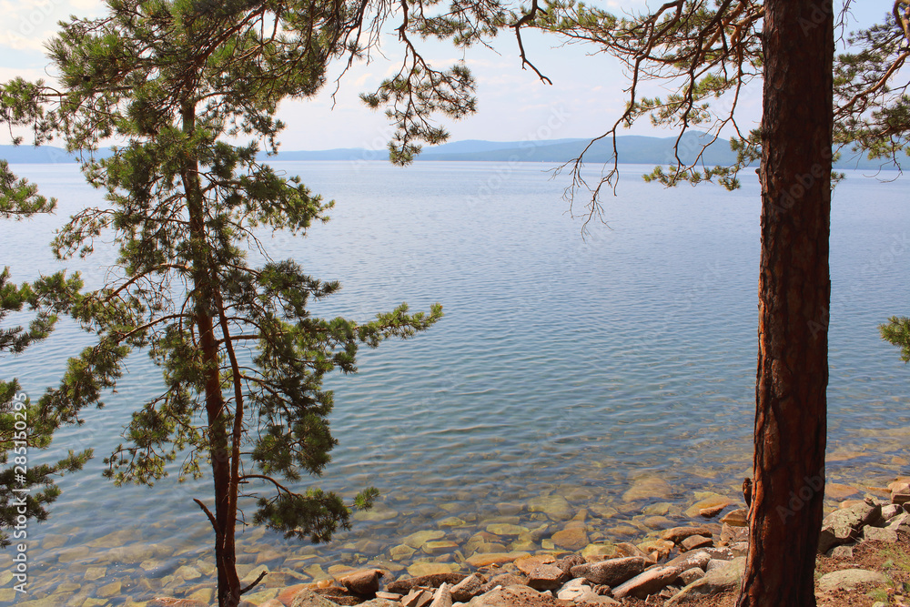 Beautiful view of the lake and mountains through the trees. Background. Landscape. Beautiful view of the lake and mountains through the trees. Background. Landscape.