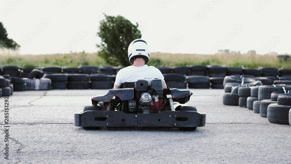 attractive male racer in protective helmet racing on the go-kart track outdoors