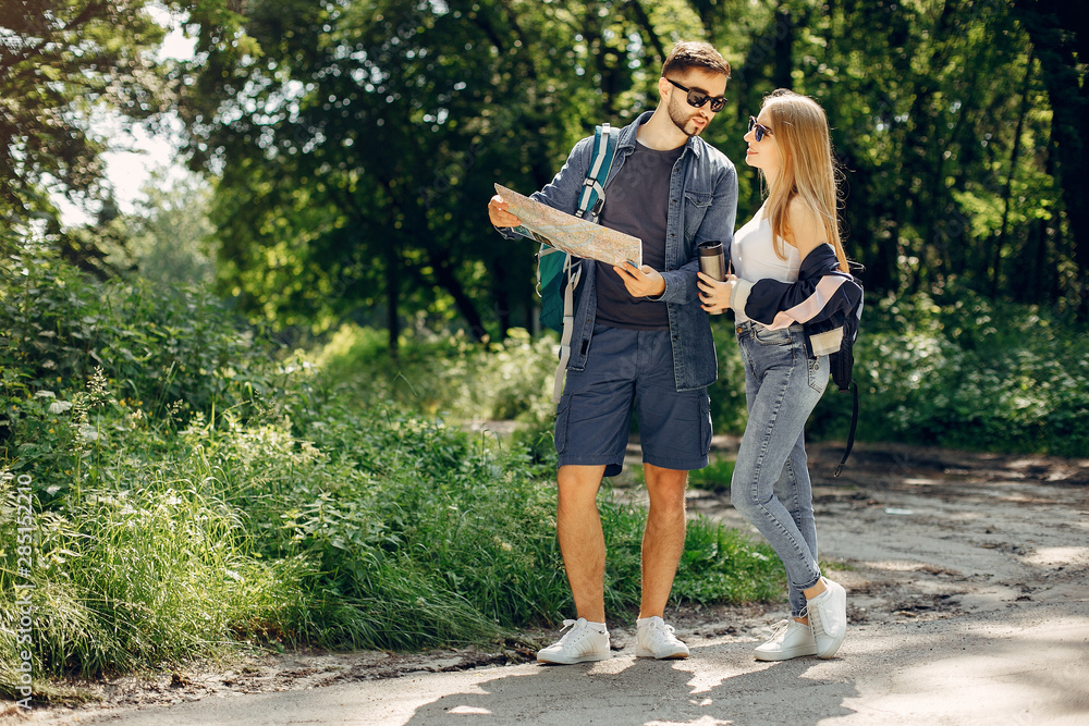Tourists in a summer forest. Couple with a map. Tourists in a summer forest. Couple with a map.