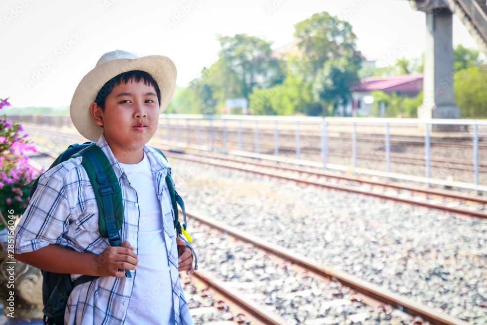 Asian little boy carrying a blue backpack Standing waiting for the train to go to school