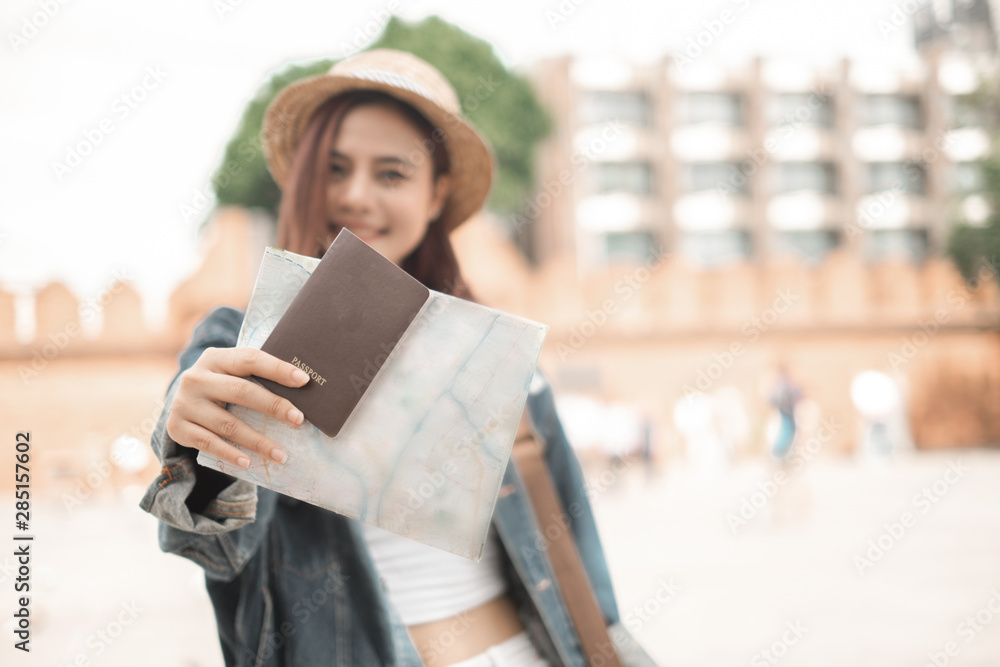 Smiling woman traveler in thapae gate landmark chiangmai thailand with backpack holding world map and passport on holiday, relaxation concept, travel concept Smiling woman traveler in thapae gate landmark chiangmai thailand with backpack holding world map and passport on holiday, relaxation concept, travel concept