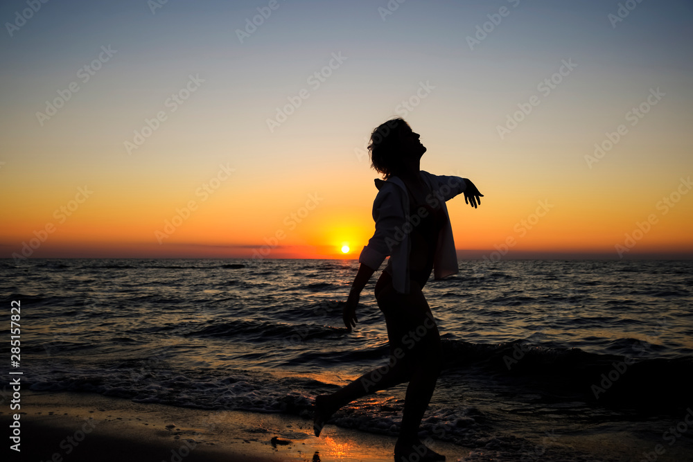 girl with a glass of champagne is dancing on the seashore.