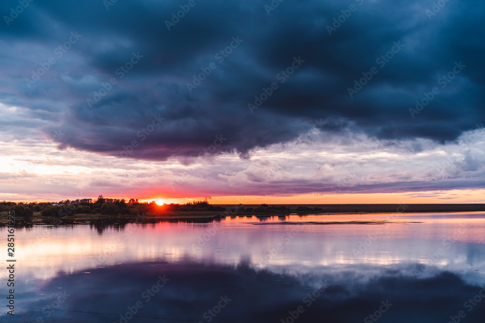 Sunset with stormy clouds reflecting in lake