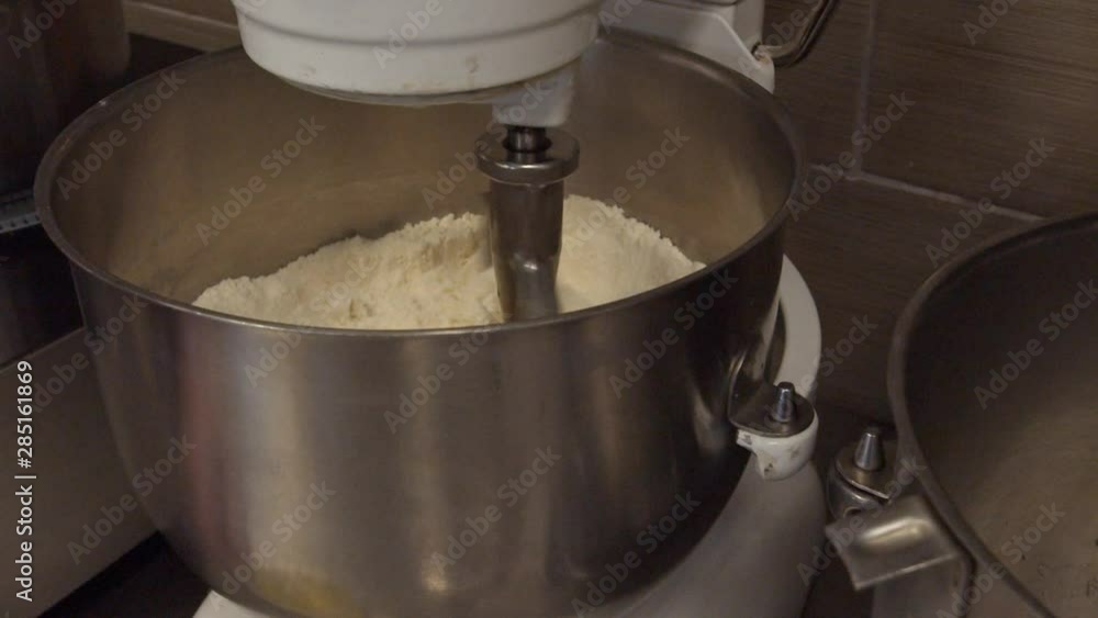 Mixing Flour in an industrial mixer during the day time in a bakery. Mixing Flour in an industrial mixer during the day time in a bakery.