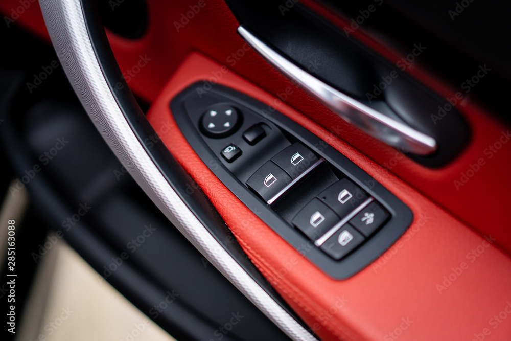 Windows and lock controller in the modern luxury car covered by beautiful red leather close up.