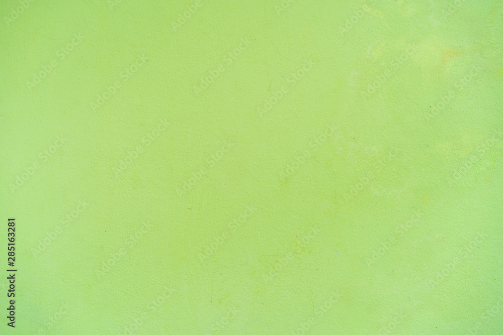 Texture of an empty concrete wall painted in bright green color background.  Empty green backgroud, backdrop, wallpaper photograph.