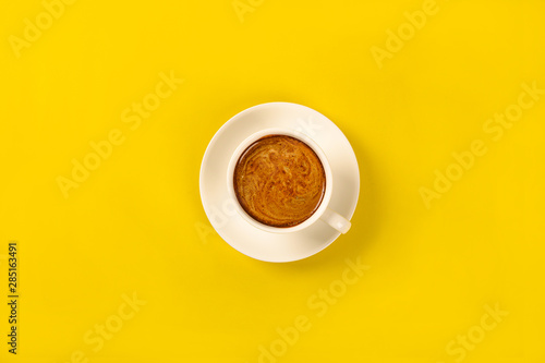 Cup of coffee o n yellow background.top view
