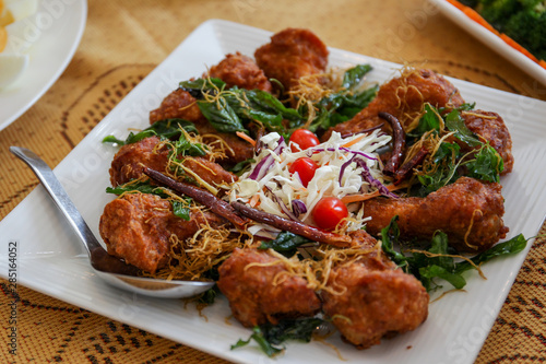 Traditional Thai spicy meat balls with herbal served on white dish on the table.