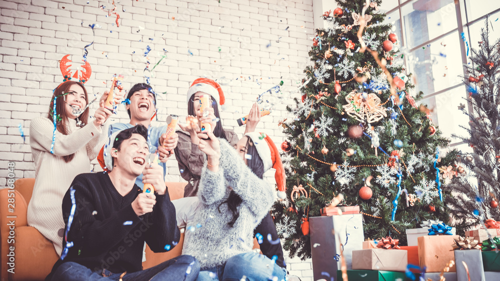 Asian people party celebrate christmas and new year eve in house and christmas tree decorate with confetti paper shoot
