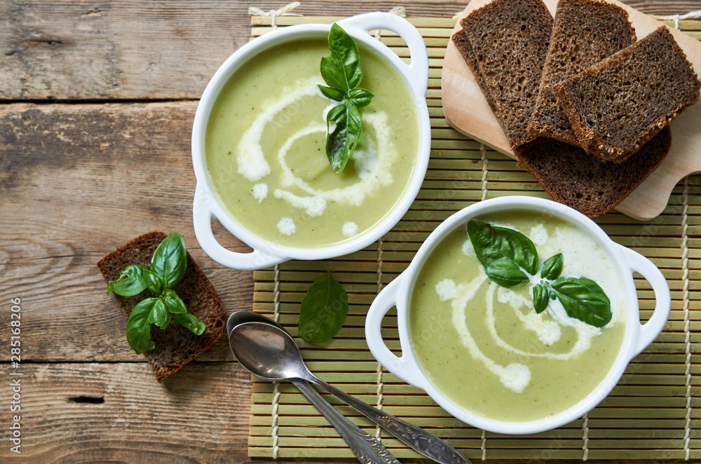 Zucchini cream soup with basil in white bowls 