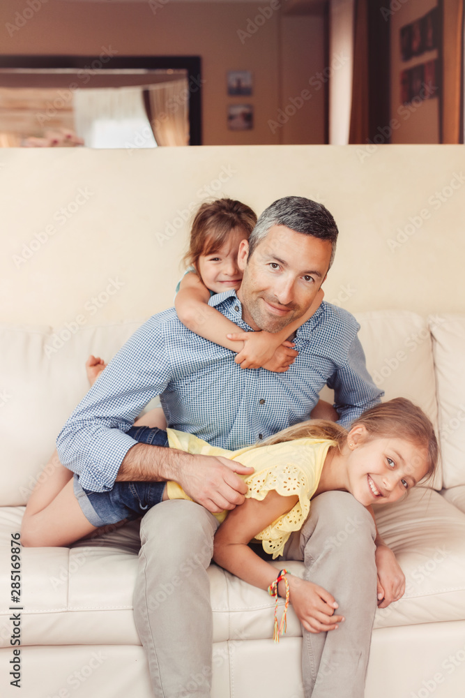 Father and daughters girls kids at home spending time together. Parent playing with children. Family having fun hugging and laughing. Real people lifestyle. Fathers day holiday concept. Father and daughters girls kids at home spending time together. Parent playing with children. Family having fun hugging and laughing. Real people lifestyle. Fathers day holiday concept.