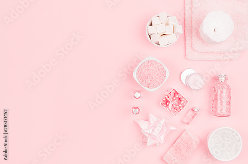 Natural skin care products, accessories for bathroom - cream, salt, essential oil, soap, towel, perfume, pearls, gift, box, bottles, bowl on pink background.