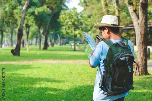 Asian male students Carrying a travel backpack, wearing a hat, holding a map to travel to learn