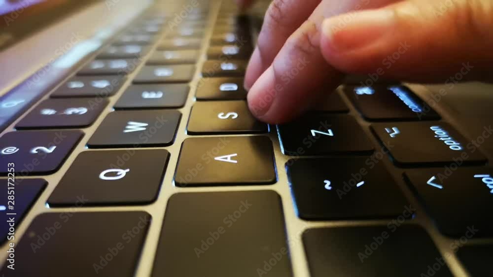 Close up shot of fingers typing on laptop keyboard and scrolling and clicking on trackpad.