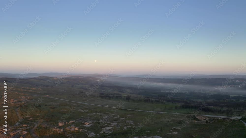 Beautiful road, crossing a mountain on a misty morning. Moon on the frame. Drone shot at sunrise on the north of Portugal Beautiful road, crossing a mountain on a misty morning. Moon on the frame. Drone shot at sunrise on the north of Portugal