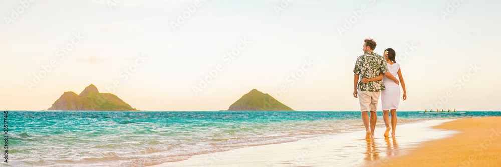 Couple walking on beach sunset vacation panoramic hawaii travel. Woman and man relaxing on tourist holiday in Lanikai, Oahu, Hawaii banner.