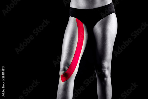Medical taping for leg muscles pain relief showed on young model.