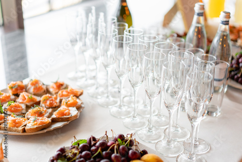 reception. Table top full of glasses of sparkling white wine with canapes and antipasti in the background. champagne bubbles