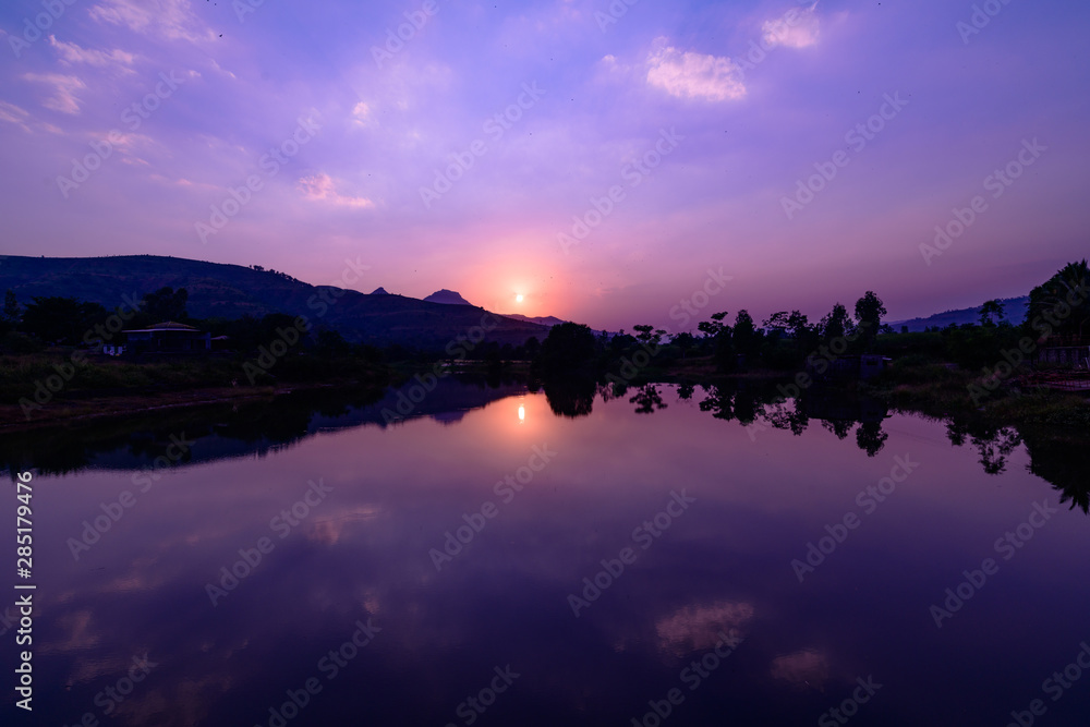 Sunset over a lake with calm waters reflecting sky