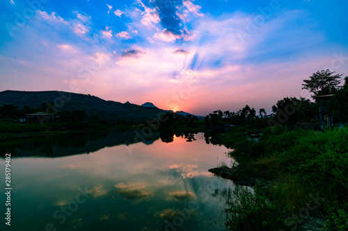 Fototapeta Naklejka Na Ścianę i Meble -  Sunset over a lake with calm waters reflecting sky