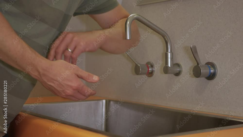 Man Washes Hands in a Hospital Sink at Night. STATIC SHOT Man Washes Hands in a Hospital Sink at Night. STATIC SHOT