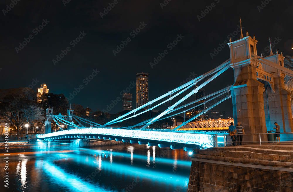 Fototapeta premium SINGAPORE - MAY 19, 2019: Cavenagh Bridge one of the oldest bridges in Singapore, that spans across the Singapore River in the Downtown by night.