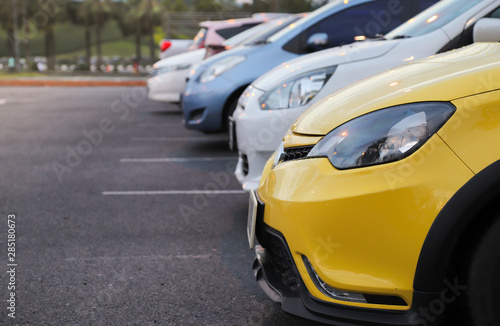 Closeup of front side of yellow car and other cars parking in parking area after raining.  © Amphon