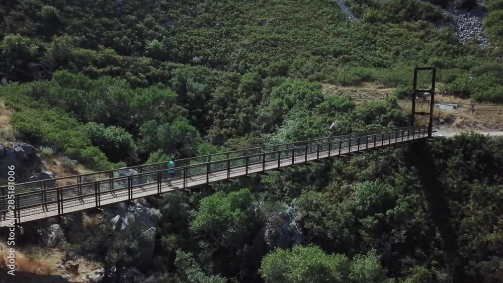 Drone Shot following an active man running on an outdoor hanging suspension bridge above Bear Canyon in Draper City, Utah. Drone Shot following an active man running on an outdoor hanging suspension bridge above Bear Canyon in Draper City, Utah.