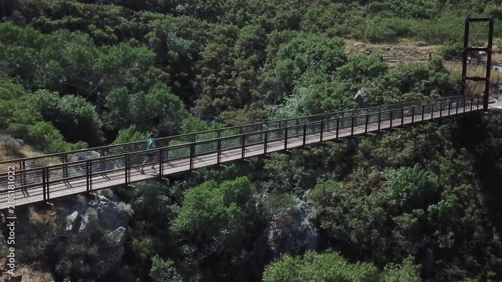 Drone Shot following an active man running on an outdoor hanging suspension bridge above Bear Canyon in Draper City, Utah. Drone Shot following an active man running on an outdoor hanging suspension bridge above Bear Canyon in Draper City, Utah.