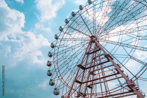 ferris wheel, attraction in the park, view from below, against the blue sky and clouds
