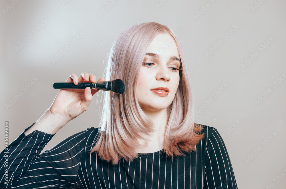 Fototapeta premium Portrait of a young pretty woman with make-up brush