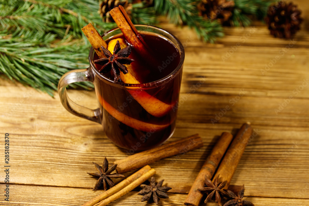 Christmas mulled wine with spices and fir tree branches and cones on wooden table Christmas mulled wine with spices and fir tree branches and cones on wooden table