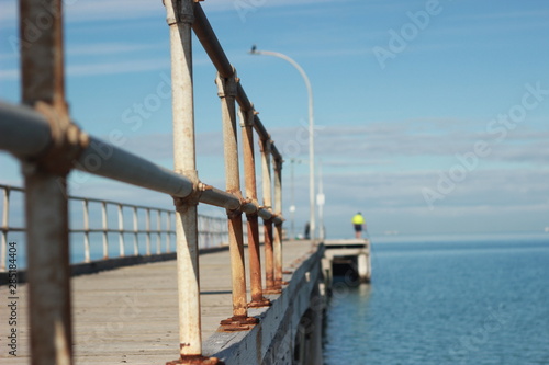 Fotografie lone man standing on an old timber jetty hobby fishing on a sunny afternoon on t