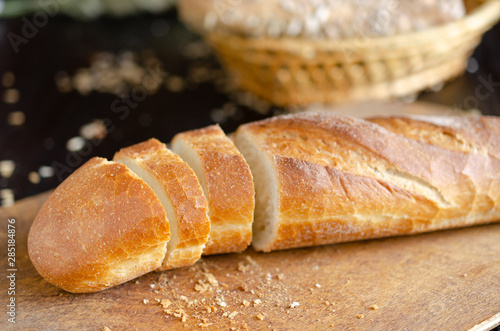 Sliced freshly baked bread on on cutting board. Kitchen utensils, organic food.