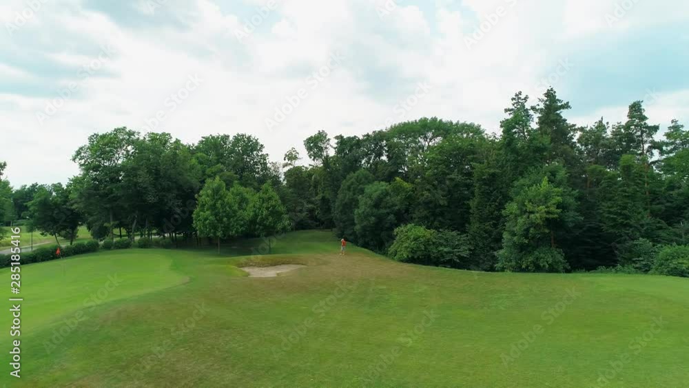Aerial view of man, who using a VR headset and playing a virtual game in the park. Young guy in helmet experiencing augmented reality on the background of nature. 4K drone footage. Aerial view of man, who using a VR headset and playing a virtual game in the park. Young guy in helmet experiencing augmented reality on the background of nature. 4K drone footage.