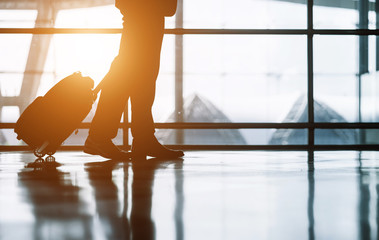 Elegant asian businessman checking email on mobile phone while walking with suitcase inside airport, experienced male employer using cell telephone while waiting for taxi car coming before work travel
