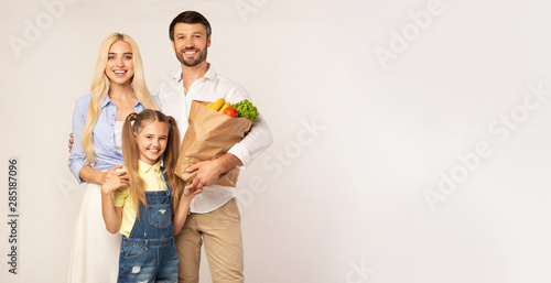 Family Posing With Grocery Shopping Bag Over White Studio Background © Prostock-studio