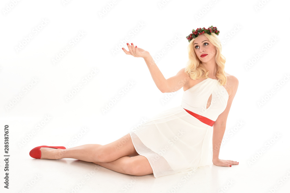 full length portrait of blonde girl wearing a white dress and flower crown. Sitting pose, isolated against a white studio background. full length portrait of blonde girl wearing a white dress and flower crown. Sitting pose, isolated against a white studio background.